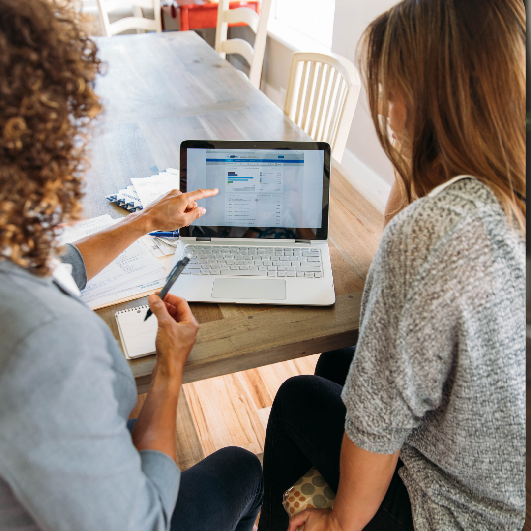 Two women looking at a laptop for financial freedom month