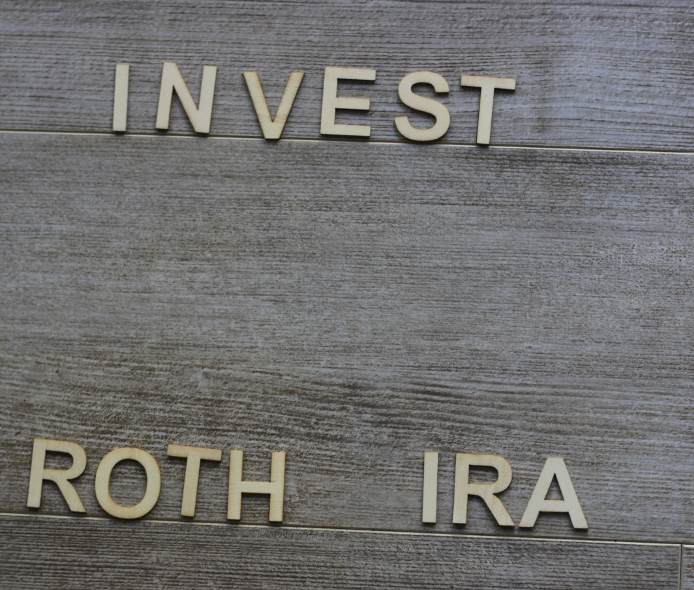 A wood background with "Invest Roth IRA" written on it for retirement planning.