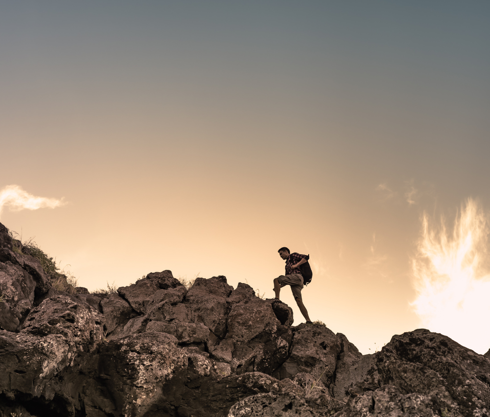 Hiker climbing up rocks for self-improvement