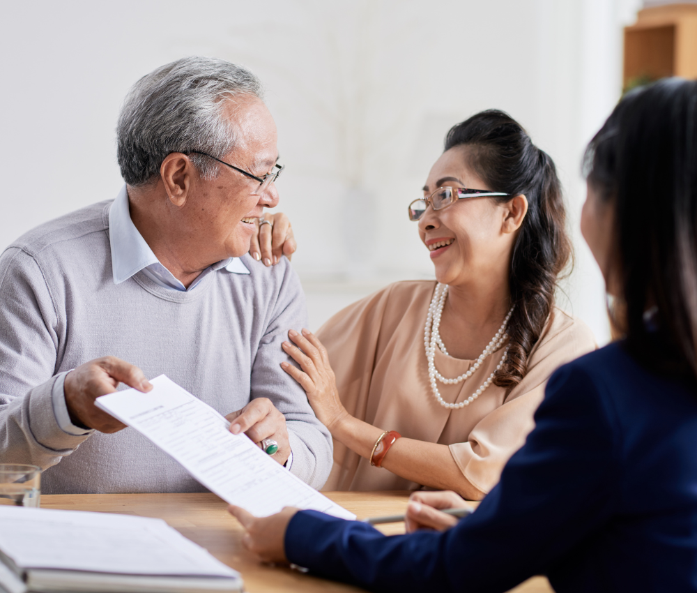 Older Asian couple looking at each other while they plan for life insurance with financial planner