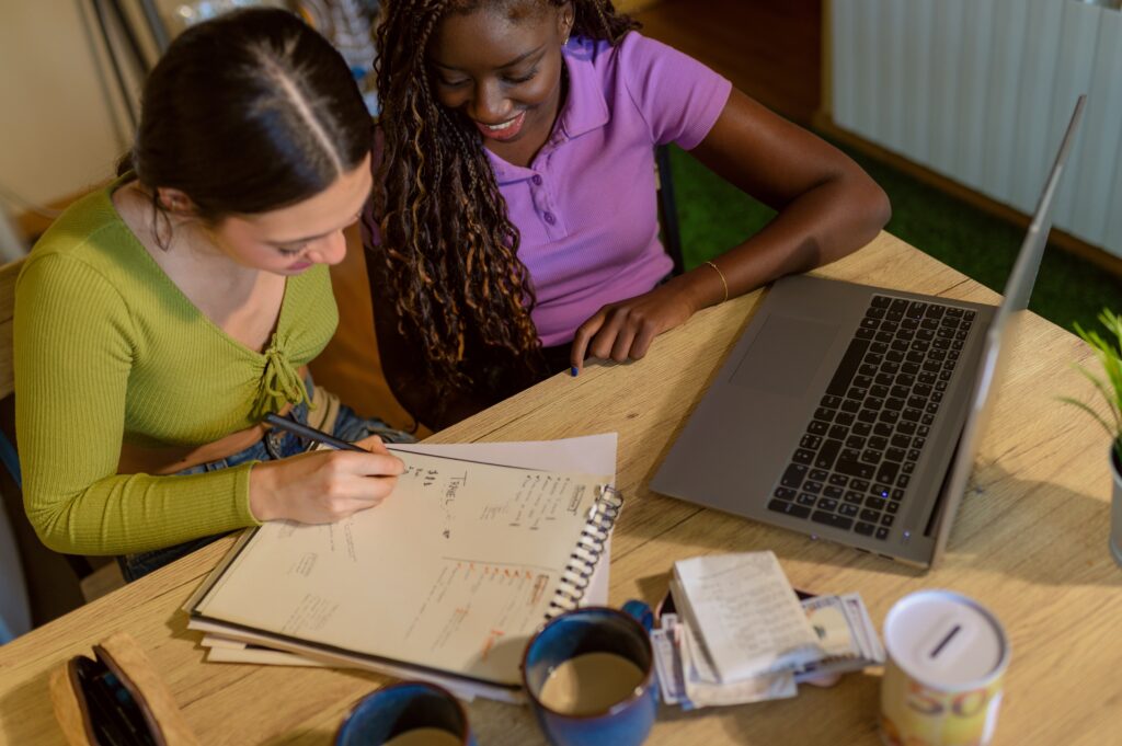 An lgbtq+ couple looking through financial planning documents by a computer