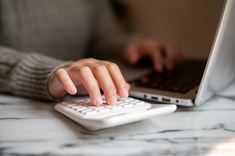 A person typing on a laptop and a calculator on a blog about education planning