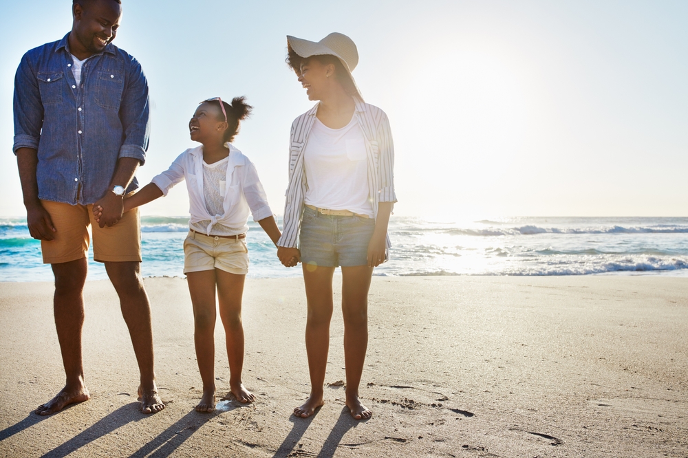 A family holding hands on the beach after getting travel insurance